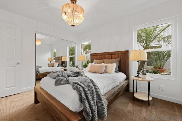 bedroom with multiple windows, a notable chandelier, and carpet