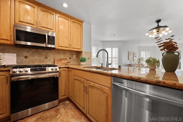 kitchen with sink, kitchen peninsula, stainless steel appliances, light stone countertops, and decorative backsplash