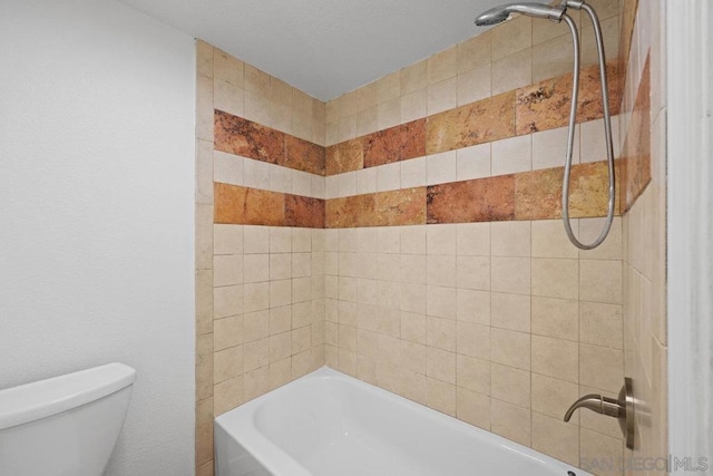 bathroom with toilet and tiled shower / bath