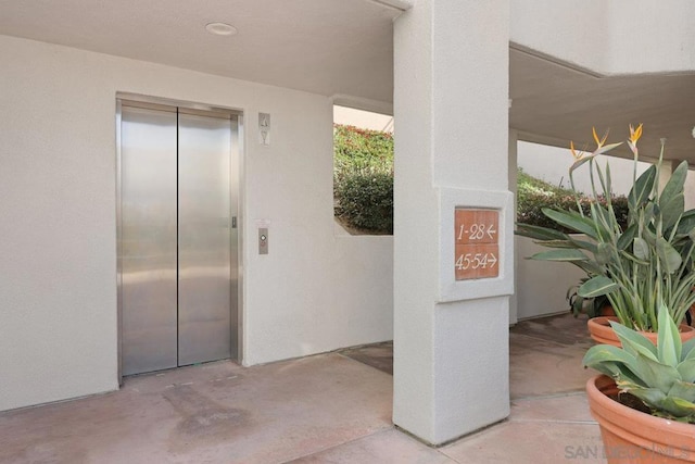 view of exterior entry featuring a patio and elevator