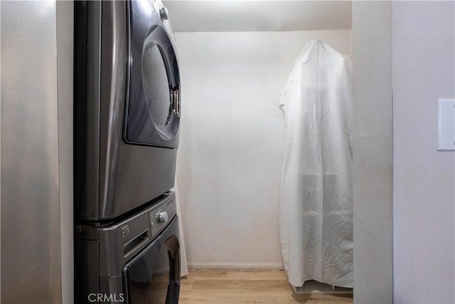 clothes washing area featuring stacked washer and clothes dryer and light hardwood / wood-style flooring