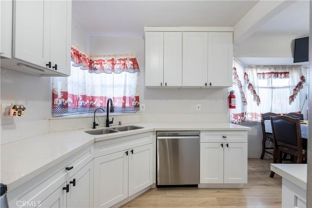 kitchen featuring dishwasher, sink, white cabinetry, and light hardwood / wood-style flooring