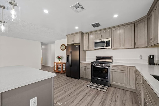 kitchen with stainless steel appliances, pendant lighting, and light hardwood / wood-style flooring