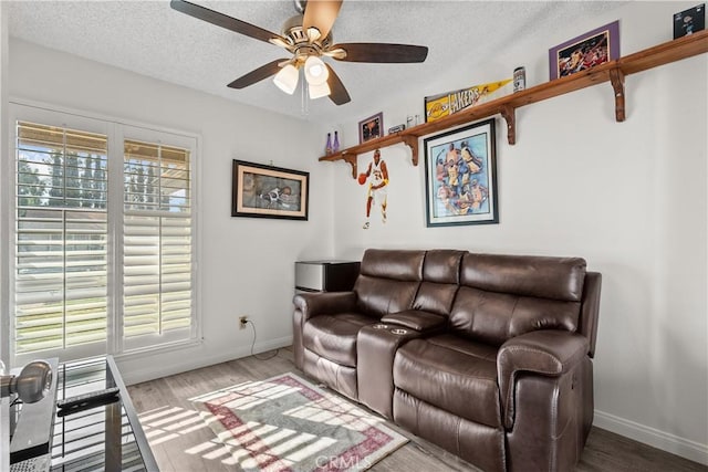 living room with a textured ceiling, ceiling fan, and hardwood / wood-style floors