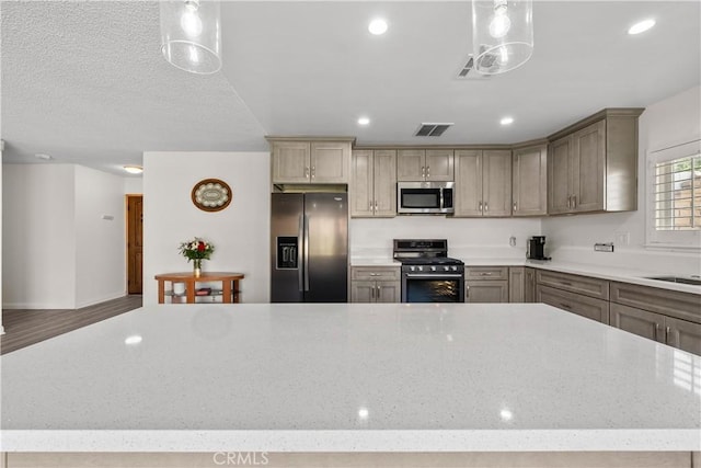 kitchen with appliances with stainless steel finishes, sink, light stone counters, and pendant lighting