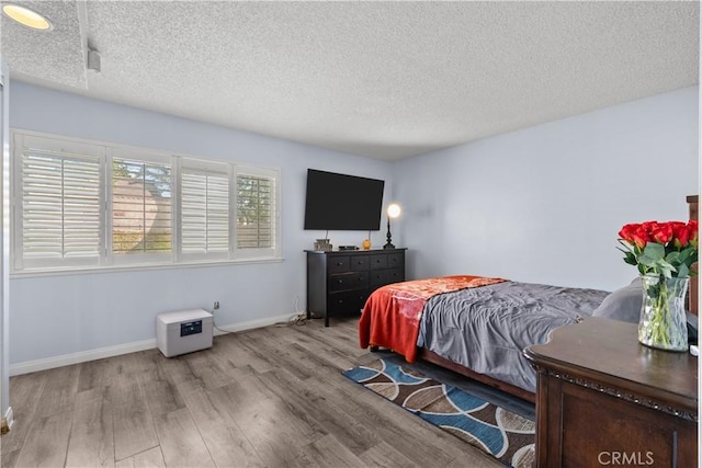 bedroom with light wood-type flooring and a textured ceiling