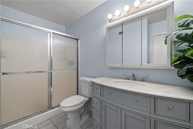 bathroom featuring toilet, vanity, tile patterned floors, and a shower with shower door