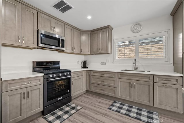 kitchen with black range with gas stovetop, light hardwood / wood-style floors, and sink