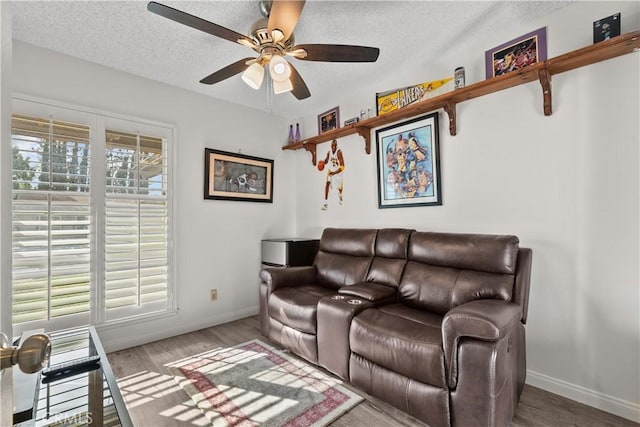 living room with a textured ceiling, ceiling fan, and wood-type flooring