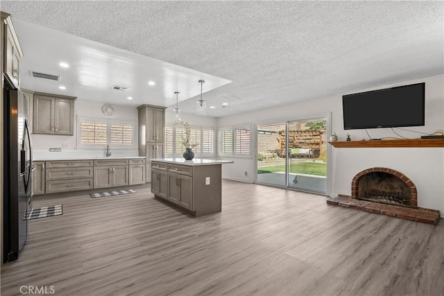 kitchen featuring pendant lighting, a center island, wood-type flooring, stainless steel refrigerator with ice dispenser, and sink