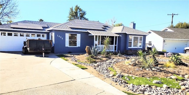 ranch-style home featuring a garage, solar panels, and a porch