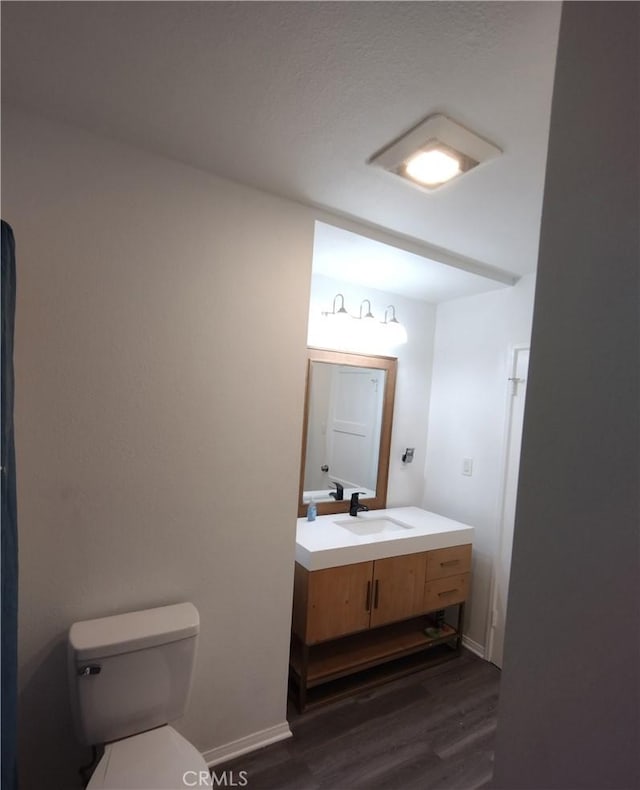 bathroom featuring wood-type flooring, toilet, and vanity