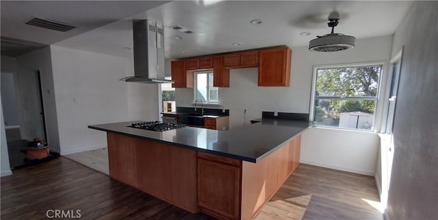 kitchen with stainless steel gas stovetop, wood-type flooring, island range hood, and kitchen peninsula