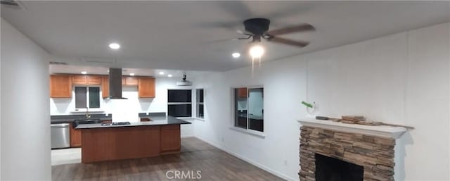 kitchen featuring ceiling fan, dark hardwood / wood-style floors, a fireplace, island exhaust hood, and stainless steel dishwasher