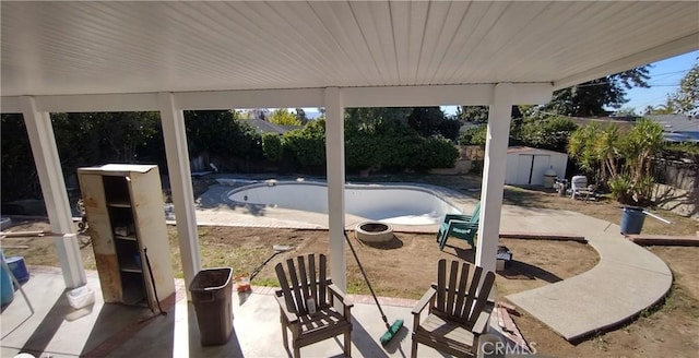 view of patio / terrace featuring an empty pool and a storage shed