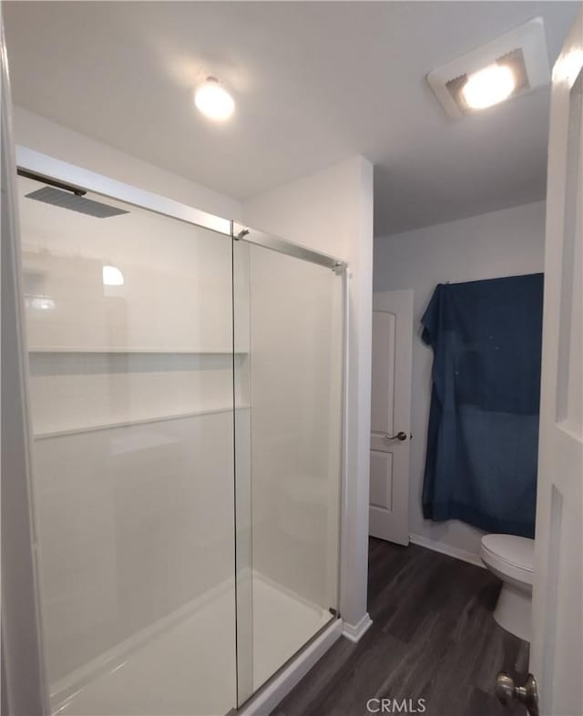 bathroom featuring wood-type flooring, toilet, and walk in shower