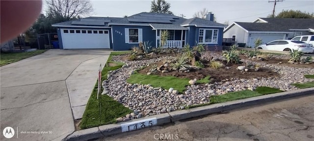 ranch-style home featuring a garage, solar panels, and covered porch