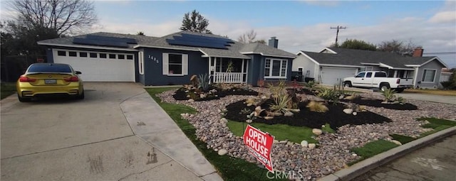 ranch-style home with a garage, covered porch, and solar panels