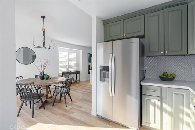 kitchen with stainless steel fridge with ice dispenser, light hardwood / wood-style floors, green cabinets, backsplash, and a notable chandelier