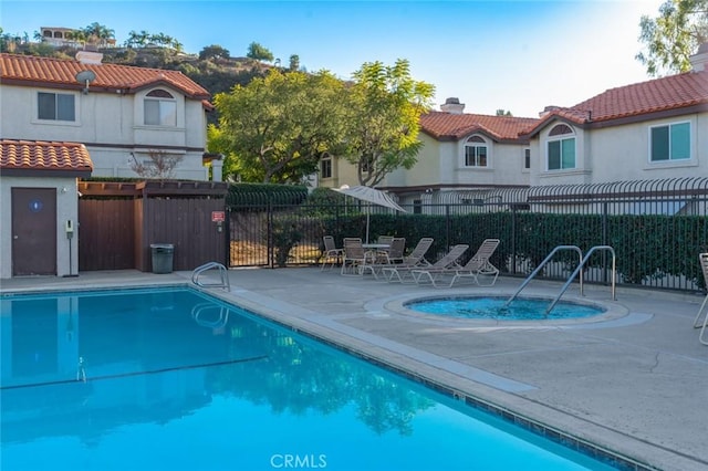 view of swimming pool featuring a patio area and a hot tub