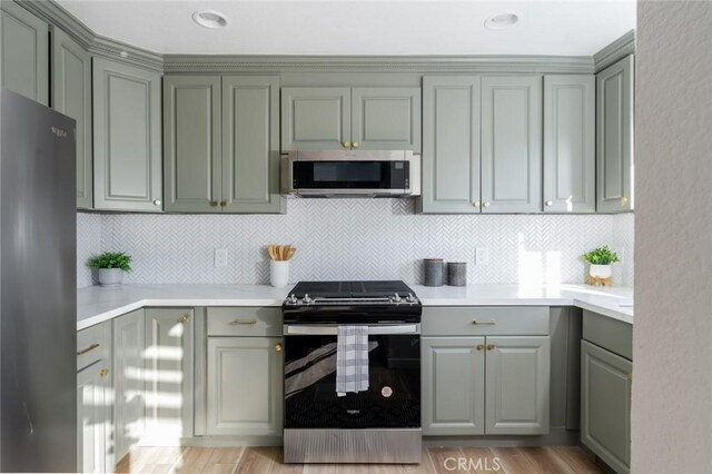 kitchen with decorative backsplash, appliances with stainless steel finishes, gray cabinets, and light hardwood / wood-style floors