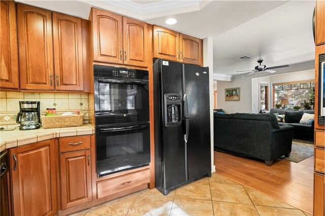 kitchen with ceiling fan, black appliances, ornamental molding, tile counters, and light tile patterned floors