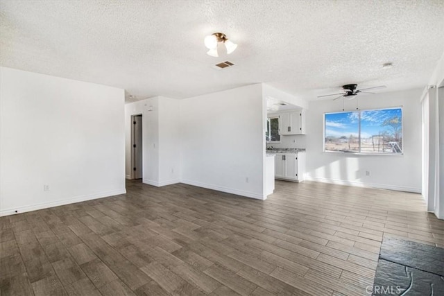 unfurnished living room featuring ceiling fan, wood-type flooring, and a textured ceiling