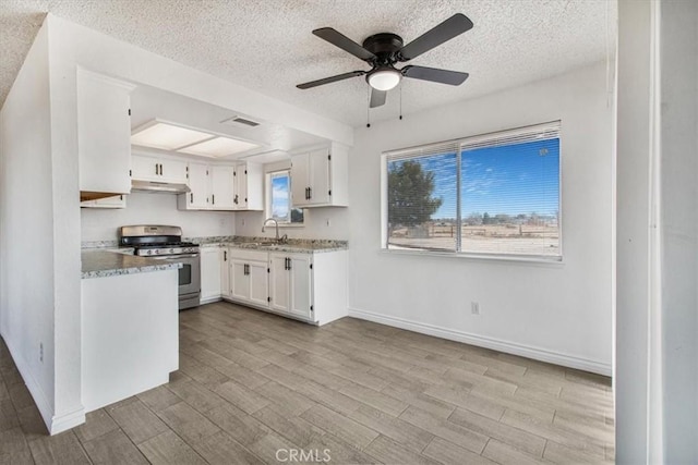 kitchen with ceiling fan, white cabinets, stainless steel range with gas cooktop, and light hardwood / wood-style floors