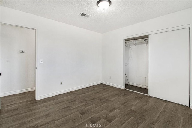 unfurnished bedroom with a closet, dark wood-type flooring, and a textured ceiling