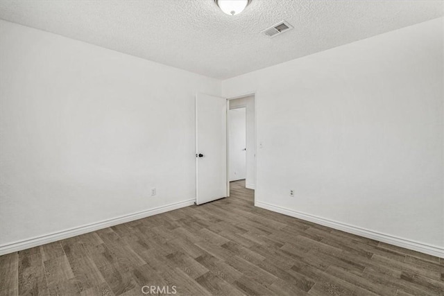 spare room with dark wood-type flooring and a textured ceiling