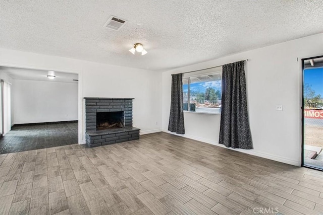 unfurnished living room featuring a brick fireplace and a textured ceiling