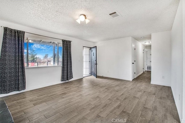 unfurnished room with a textured ceiling and light hardwood / wood-style floors