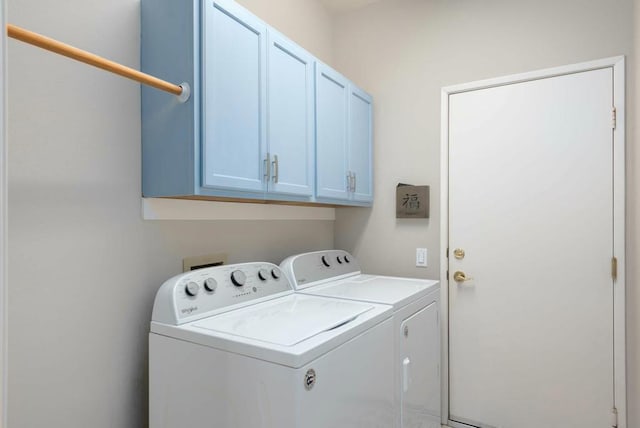 clothes washing area with washer and dryer and cabinets