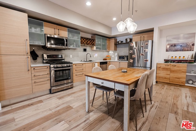 kitchen with light wood-type flooring, backsplash, sink, and stainless steel appliances