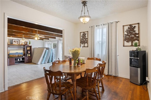 dining space with plenty of natural light, a textured ceiling, dark hardwood / wood-style floors, and beam ceiling