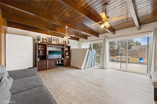 unfurnished living room with a healthy amount of sunlight, light hardwood / wood-style flooring, beamed ceiling, and ceiling fan