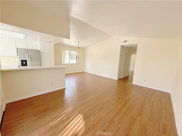 unfurnished living room featuring lofted ceiling and light hardwood / wood-style floors