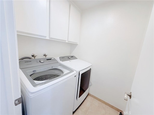 laundry area with washer and clothes dryer, light tile patterned floors, and cabinets