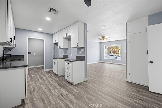 kitchen with ceiling fan, sink, white cabinets, and light hardwood / wood-style flooring