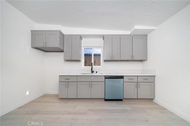 kitchen with dishwasher, gray cabinets, sink, light wood-type flooring, and a textured ceiling