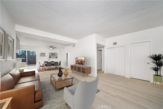 living room with ceiling fan, light hardwood / wood-style floors, and a textured ceiling