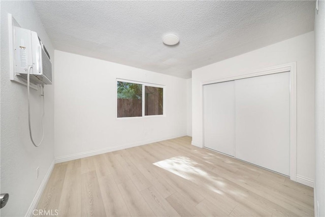 unfurnished bedroom featuring a textured ceiling, a closet, and light wood-type flooring