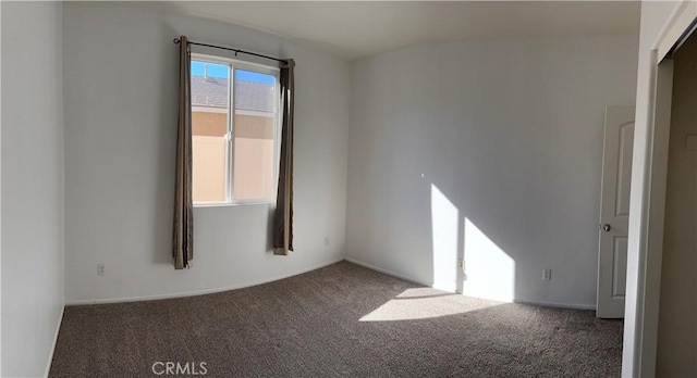 spare room with dark colored carpet