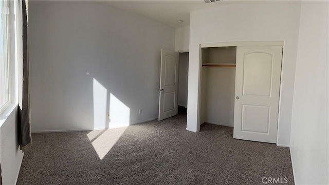 unfurnished bedroom featuring a closet and dark carpet