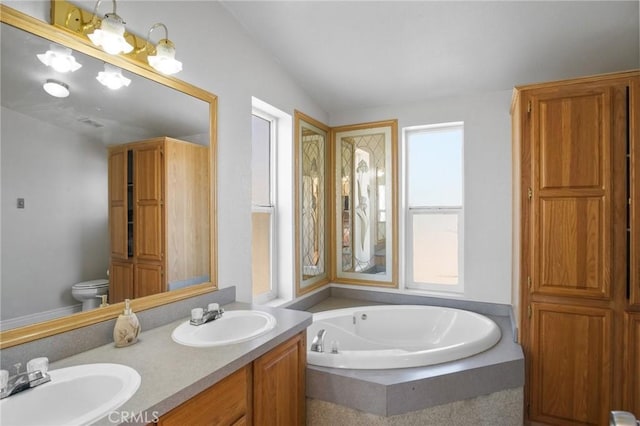 bathroom featuring tiled bath, vanity, toilet, and lofted ceiling