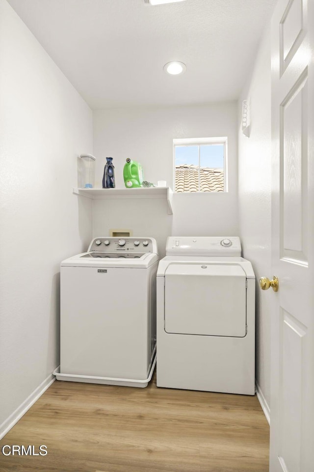 laundry room featuring washing machine and clothes dryer and light hardwood / wood-style flooring