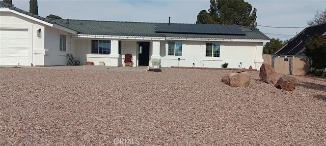 rear view of property with solar panels and a garage