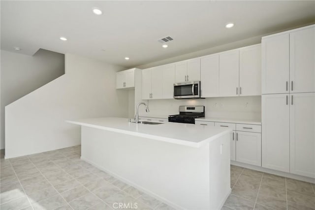 kitchen featuring sink, light tile patterned floors, a kitchen island with sink, appliances with stainless steel finishes, and white cabinets