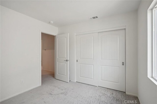 unfurnished bedroom featuring light colored carpet and a closet