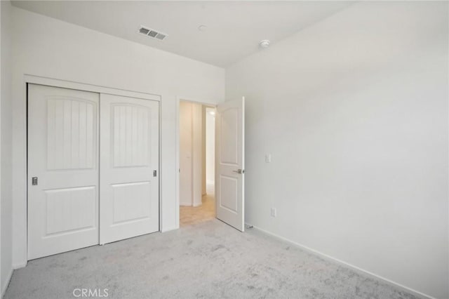 unfurnished bedroom with light carpet and a closet